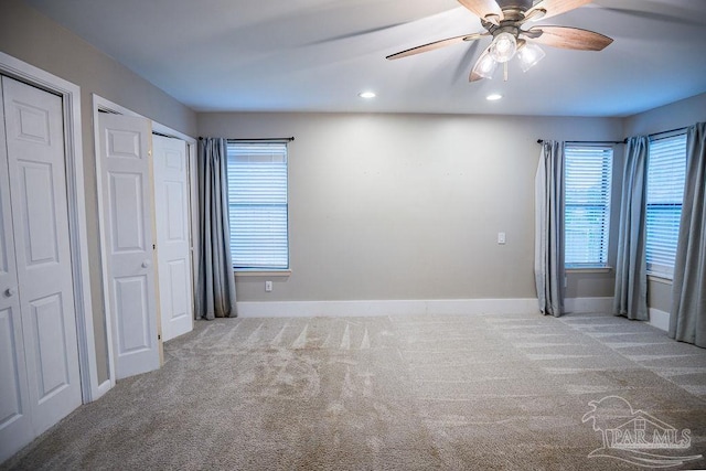 unfurnished bedroom featuring two closets, ceiling fan, and carpet floors