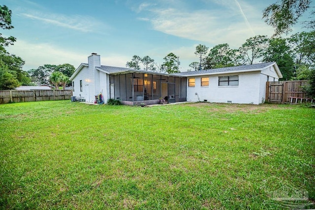 back of property with a lawn and a sunroom