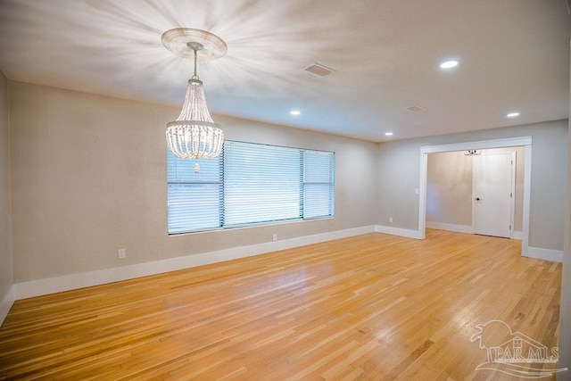 empty room with light hardwood / wood-style floors and a chandelier