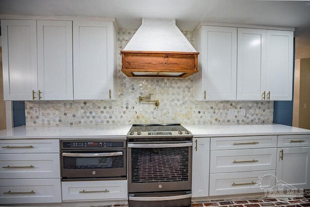 kitchen with tasteful backsplash, appliances with stainless steel finishes, premium range hood, and white cabinets