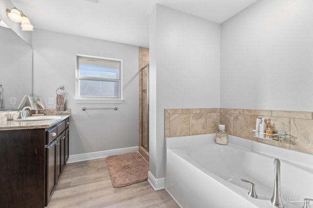 6743 Desoto St, Navarre, FL 32566 - bathroom with vanity, a garden tub, a shower stall, wood finished floors, and baseboards