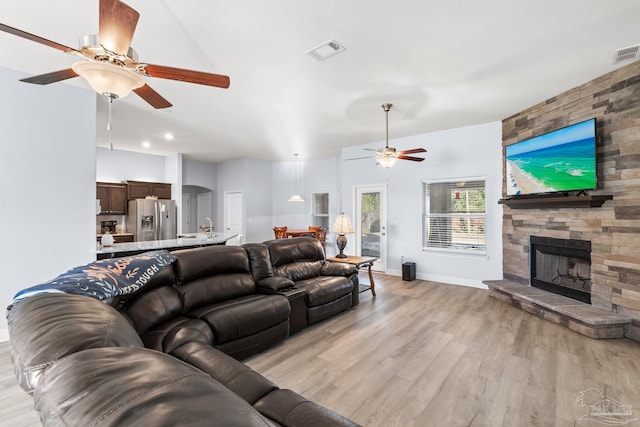 6743 Desoto St, Navarre, FL 32566 - living room with a ceiling fan, light wood finished floors, a stone fireplace, and baseboards