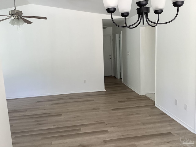 spare room featuring light wood finished floors, ceiling fan with notable chandelier, and baseboards