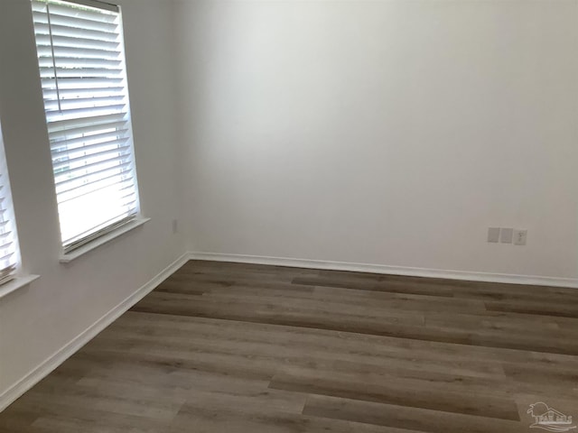 spare room featuring baseboards and dark wood-type flooring