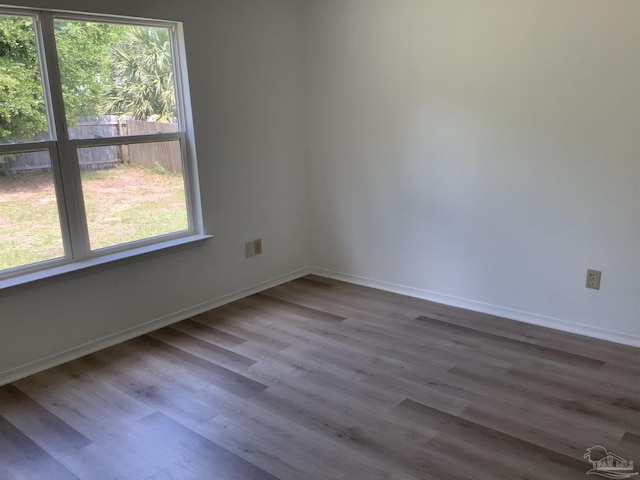 unfurnished room featuring plenty of natural light, wood finished floors, and baseboards