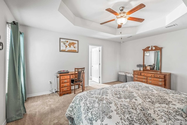 carpeted bedroom with a tray ceiling and ceiling fan