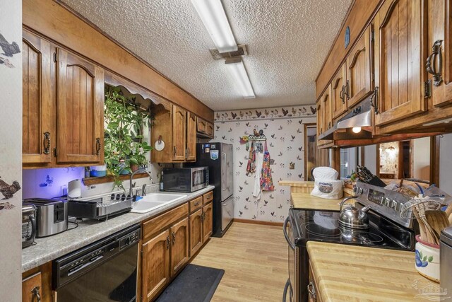 kitchen featuring light countertops, a textured ceiling, brown cabinetry, stainless steel appliances, and under cabinet range hood