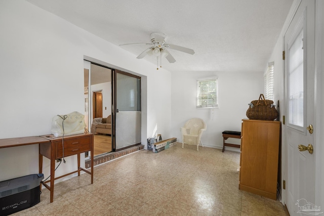 living area with ceiling fan and baseboards