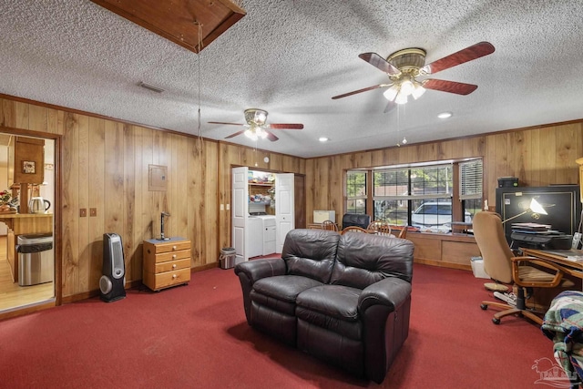carpeted living area with independent washer and dryer, wooden walls, a textured ceiling, a ceiling fan, and visible vents