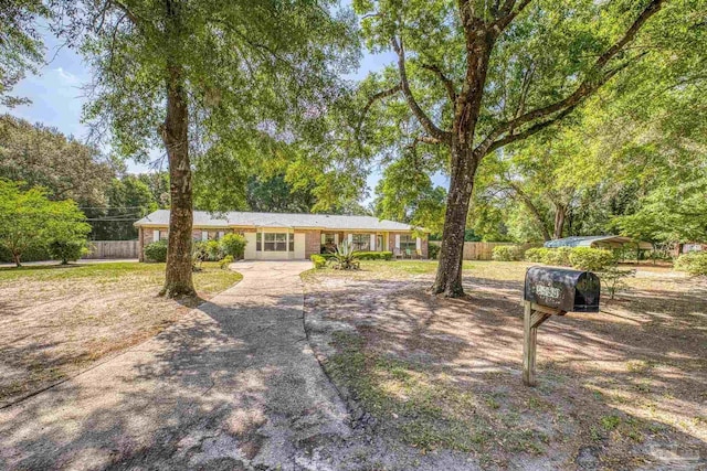 ranch-style home featuring concrete driveway and fence