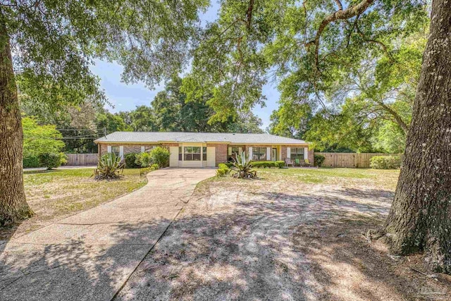 ranch-style house featuring fence, concrete driveway, a front lawn, and brick siding