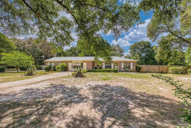 ranch-style house featuring brick siding, fence, driveway, and a front lawn
