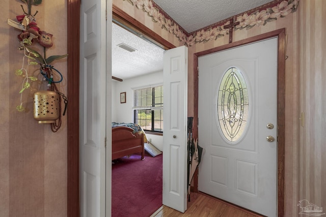 foyer featuring visible vents, light wood-style flooring, and a textured ceiling