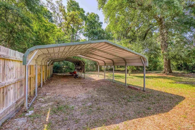 view of vehicle parking featuring fence and a detached carport