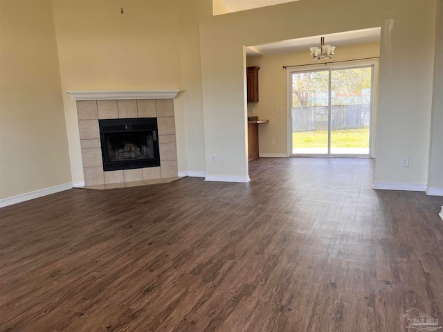 unfurnished living room featuring a fireplace, a notable chandelier, and dark hardwood / wood-style floors