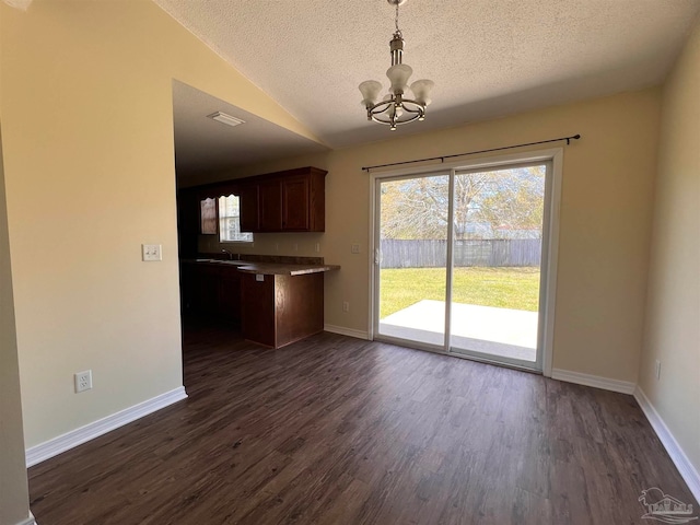 interior space with a textured ceiling, dark hardwood / wood-style floors, an inviting chandelier, hanging light fixtures, and sink