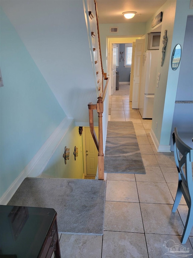 hall featuring light tile patterned floors, baseboards, and visible vents