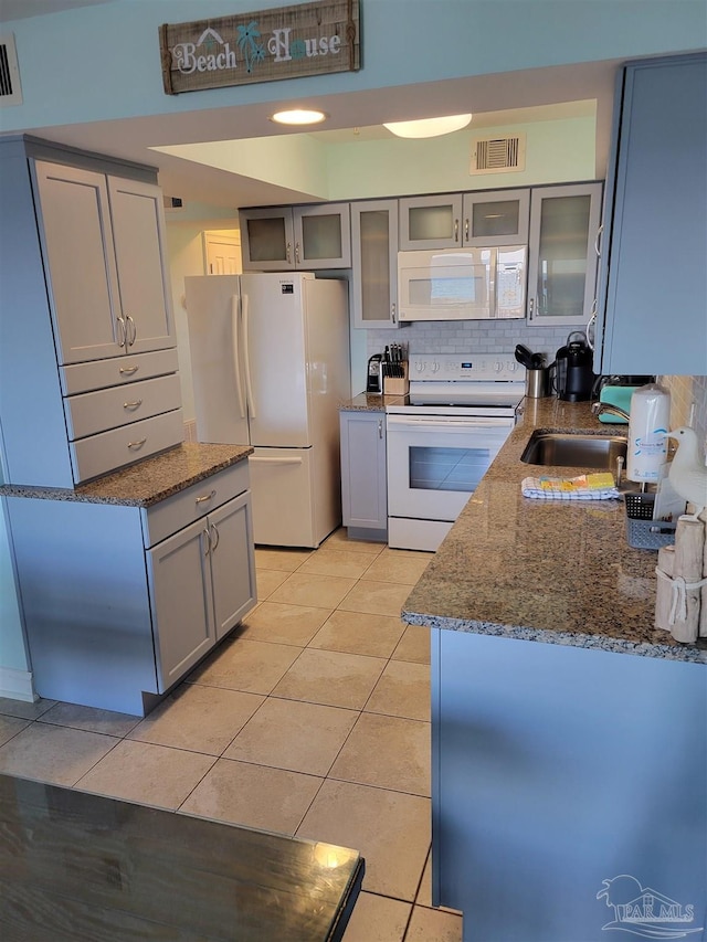 kitchen with light tile patterned flooring, white appliances, a sink, visible vents, and dark stone countertops