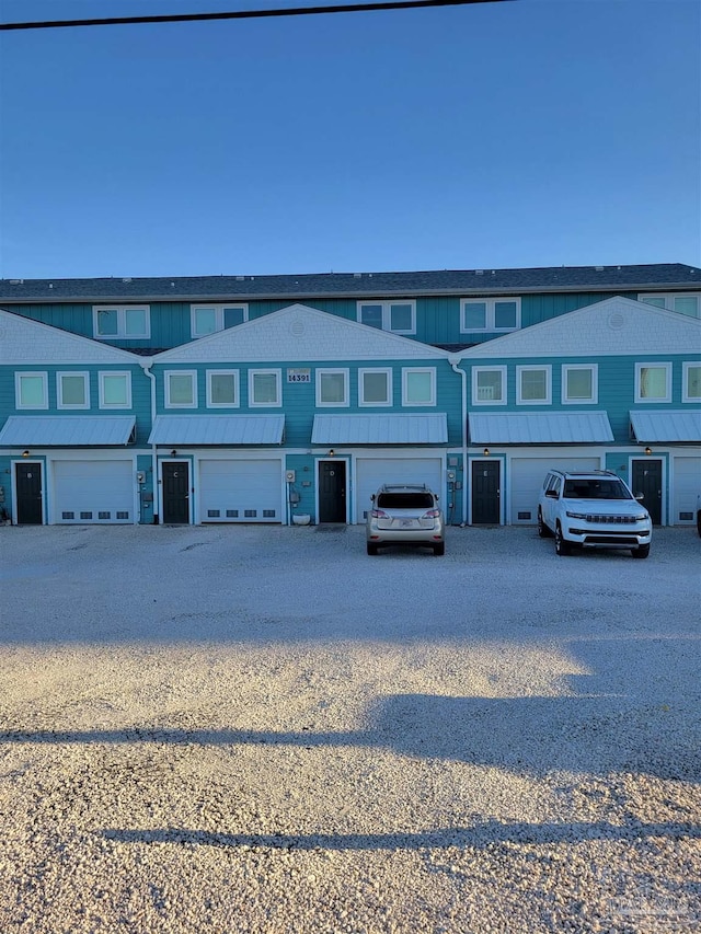 multi unit property featuring a standing seam roof, driveway, and an attached garage