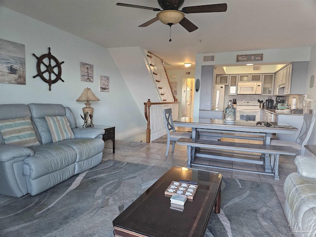 living area with ceiling fan, visible vents, baseboards, stairs, and tile patterned floors