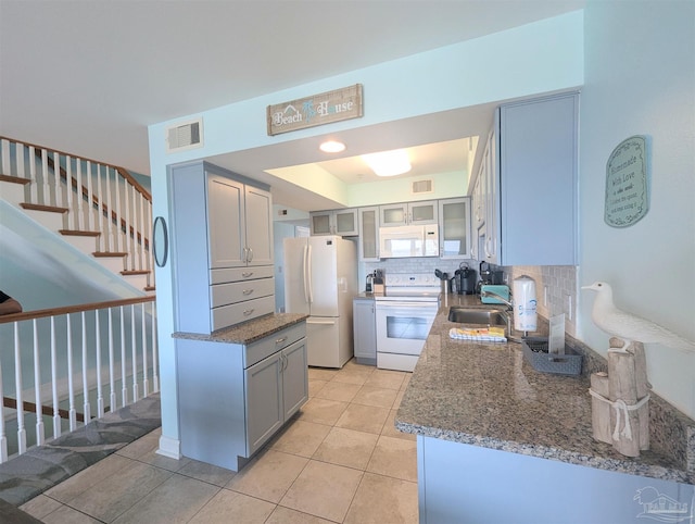 kitchen with white appliances, tasteful backsplash, visible vents, gray cabinets, and a sink