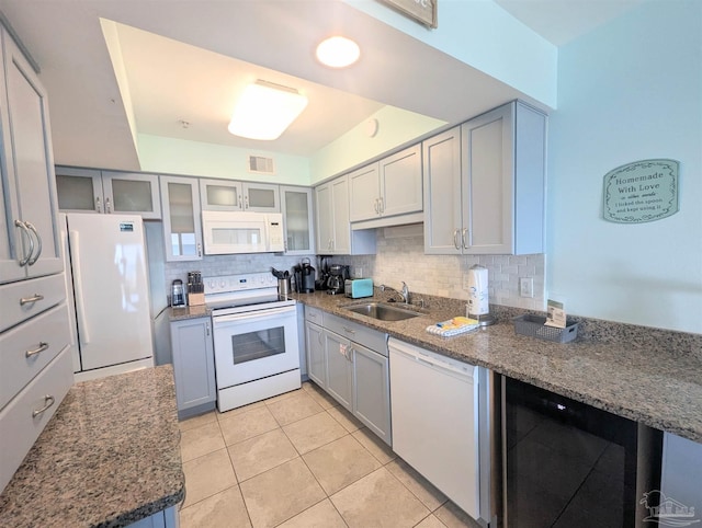 kitchen featuring white appliances, visible vents, decorative backsplash, gray cabinetry, and a sink