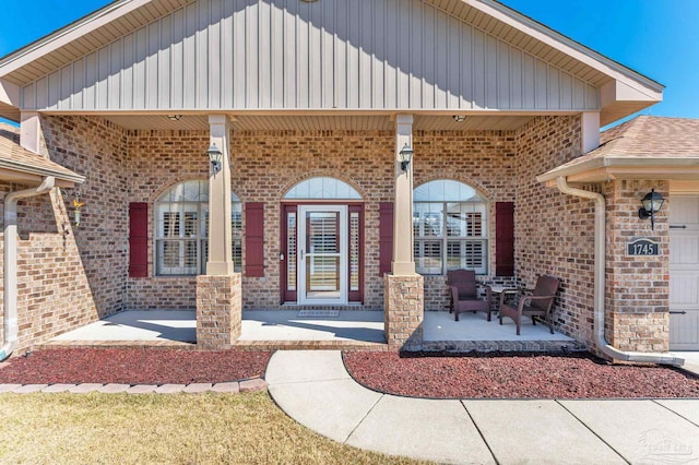 view of exterior entry featuring covered porch and brick siding