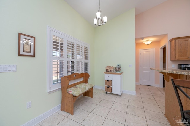 living area with high vaulted ceiling, a notable chandelier, baseboards, and light tile patterned floors