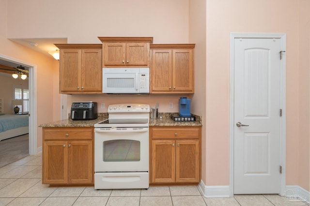 kitchen with stone countertops, white appliances, brown cabinets, and light tile patterned floors