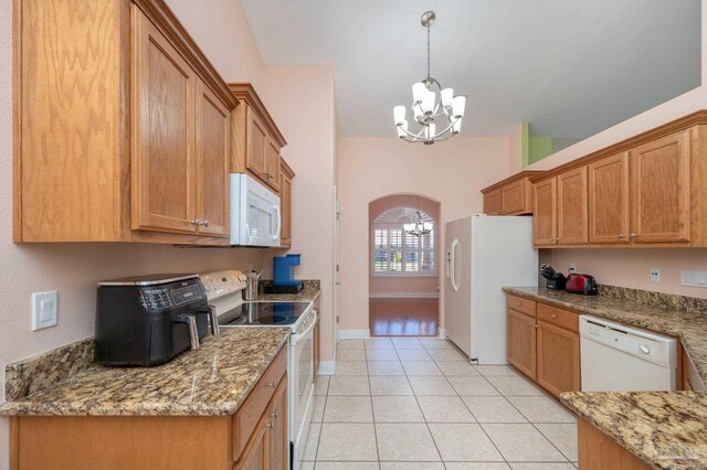 kitchen with brown cabinets, white appliances, a chandelier, and arched walkways