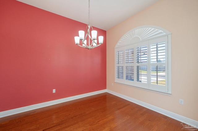 unfurnished room featuring a notable chandelier, vaulted ceiling, wood finished floors, and baseboards