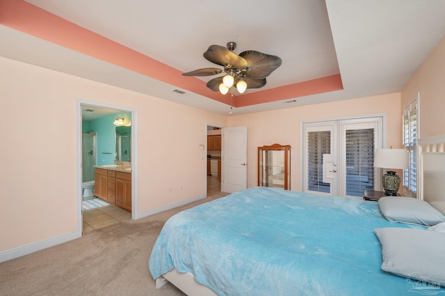 bedroom with access to exterior, a tray ceiling, visible vents, light carpet, and baseboards