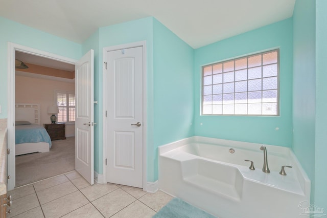 ensuite bathroom featuring baseboards, tile patterned flooring, a bath, and connected bathroom