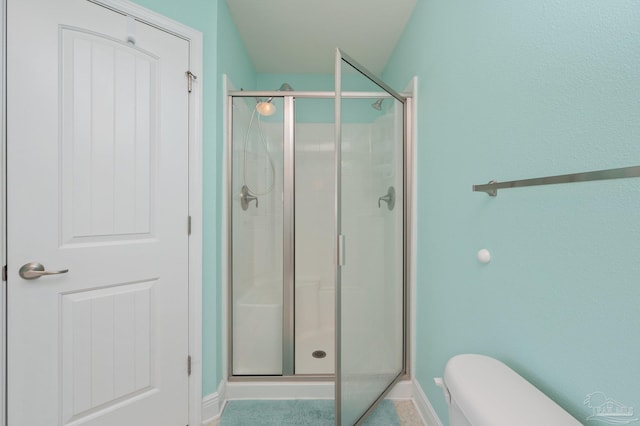 full bathroom featuring toilet, a stall shower, and baseboards