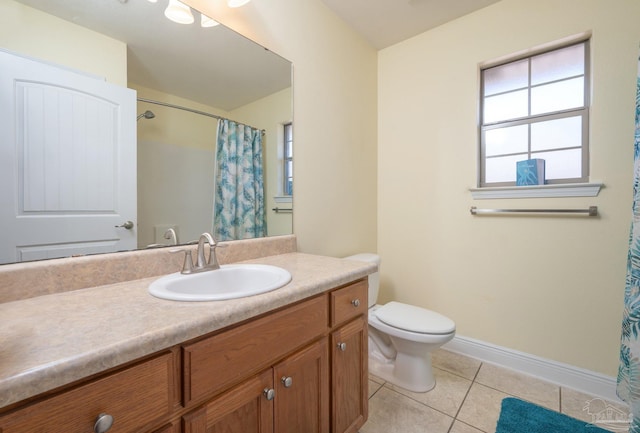 bathroom with toilet, vanity, tile patterned flooring, and a wealth of natural light