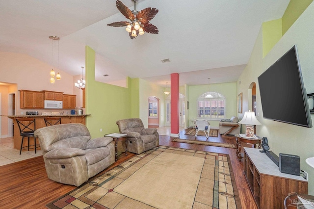 living area featuring lofted ceiling, ceiling fan with notable chandelier, and light wood-style floors