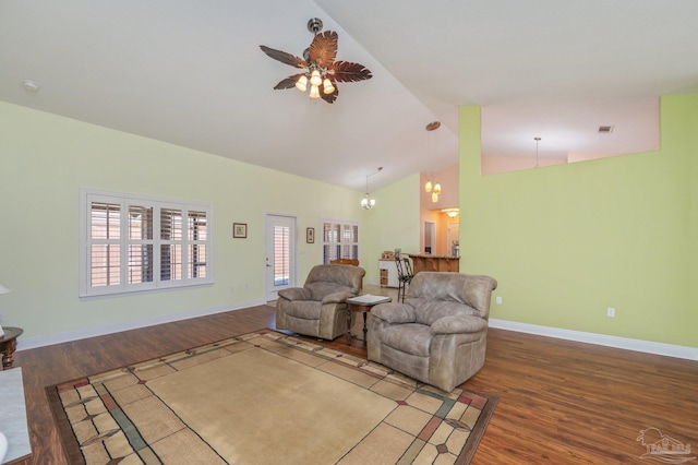 living area with ceiling fan with notable chandelier, high vaulted ceiling, wood finished floors, and baseboards