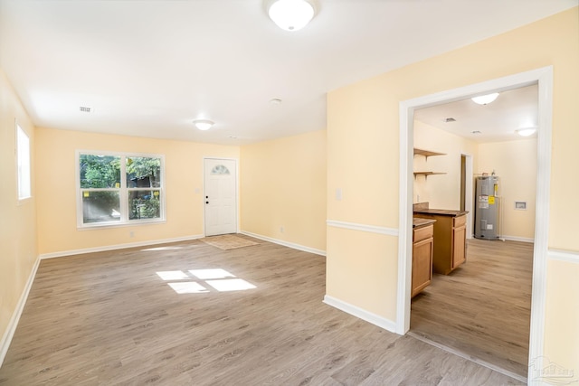 empty room with light hardwood / wood-style floors and electric water heater