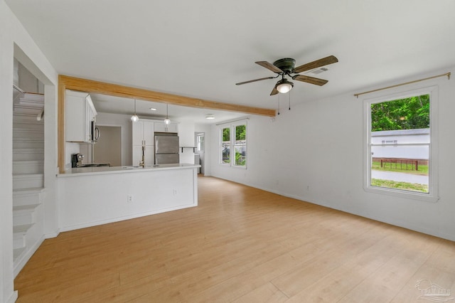 unfurnished living room featuring ceiling fan, beamed ceiling, light wood-style flooring, and visible vents