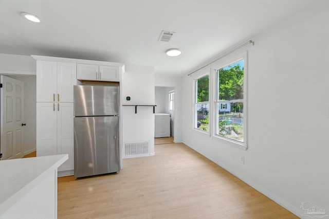 kitchen featuring visible vents, freestanding refrigerator, white cabinetry, and light wood-style flooring