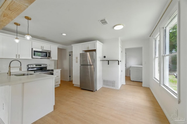 kitchen with visible vents, a sink, washer / clothes dryer, and stainless steel appliances