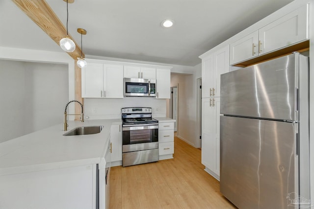 kitchen with a sink, light countertops, stainless steel appliances, white cabinetry, and a peninsula
