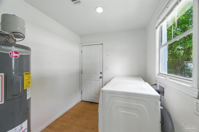 laundry room featuring laundry area, independent washer and dryer, baseboards, light wood-style floors, and electric water heater