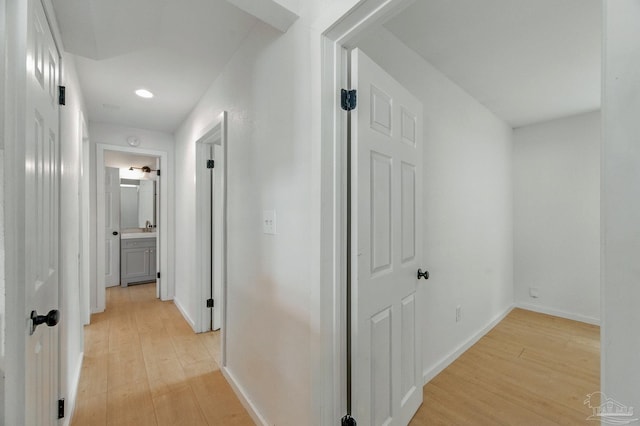 corridor with light wood-type flooring, recessed lighting, and baseboards