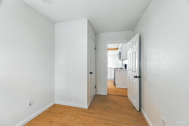 hall with baseboards and light wood-style flooring