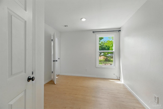 unfurnished room featuring light wood-style floors, baseboards, and visible vents