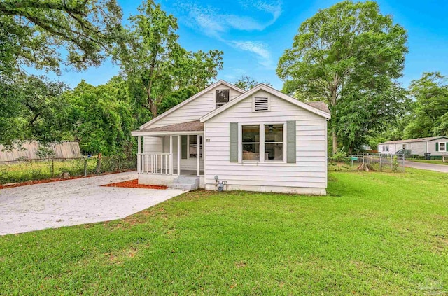 back of property with a shingled roof, a yard, covered porch, and fence