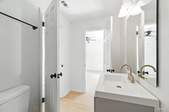 bathroom with ceiling fan, visible vents, vanity, baseboards, and toilet