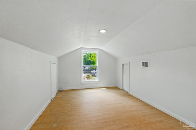 additional living space with visible vents, light wood finished floors, baseboards, and vaulted ceiling