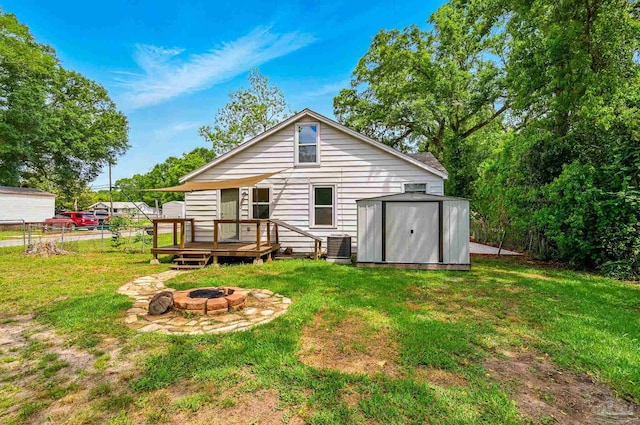 back of house with a lawn, a wooden deck, a storage unit, and an outdoor fire pit